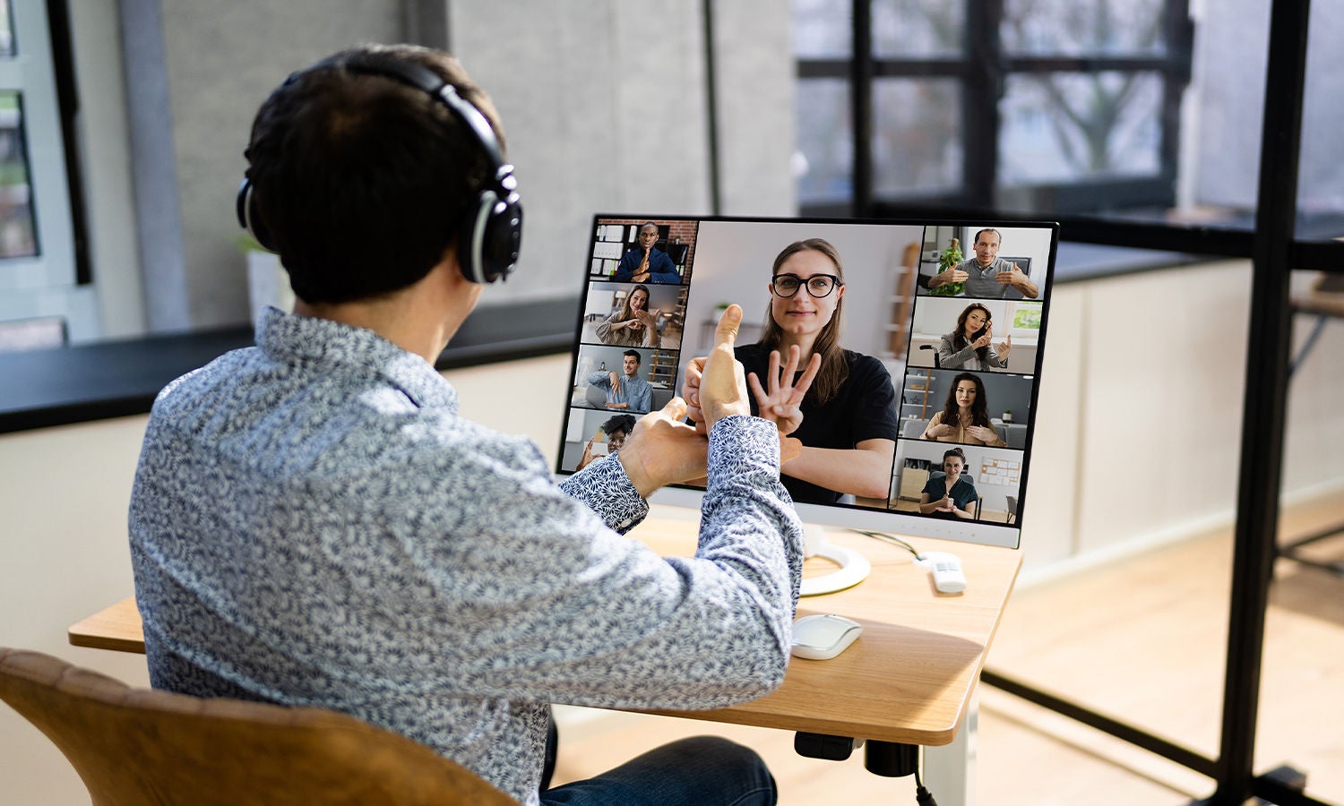 A person wearing headphones and using sign language to communicate on a virtual call